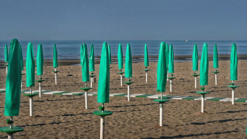 Multi colored deck chairs on beach against clear sky