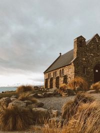 Old house by building against sky