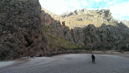 Man on rock by road against sky