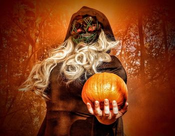 Midsection of woman holding pumpkin during halloween