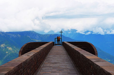 Pier on mountain against cloudy sky