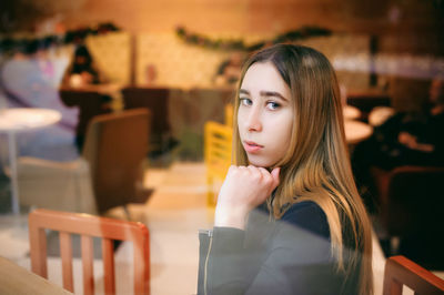 Close-up portrait of young woman sitting at cafe seen through window
