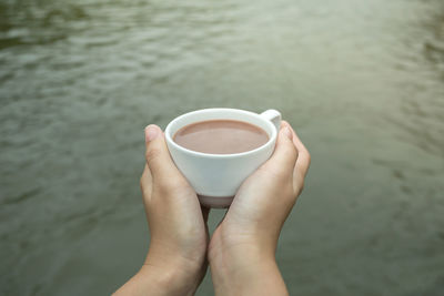 High angle view of hand holding coffee cup