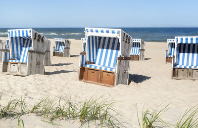 Hooded chairs on beach against sky