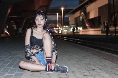 Portrait of young woman sitting in city