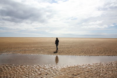 Rear view of man walking on sand at beach