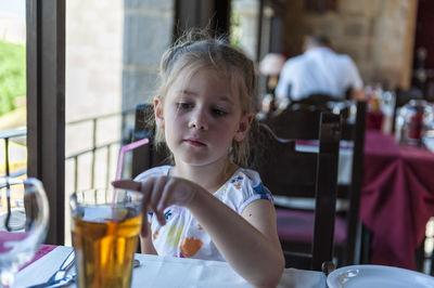 Girl having drink while sitting at table in restaurant