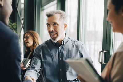 Mature businessman greeting young colleague in meeting at office