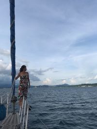 Woman standing on boat in sea against blue sky
