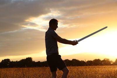 Man standing on field against sky during sunset