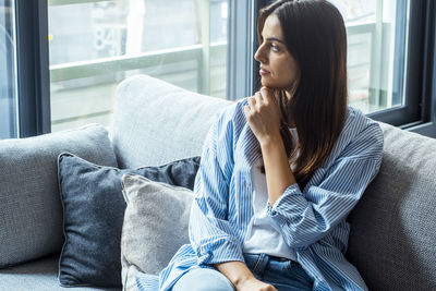 Young woman sitting on sofa at home