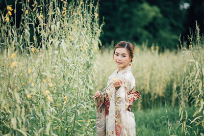 Portrait of smiling young woman standing on field