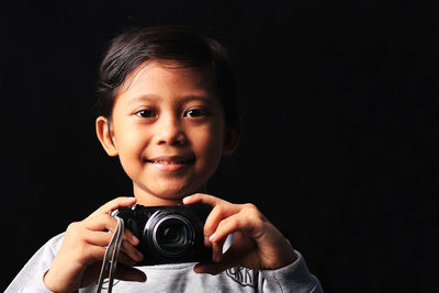 Portrait of boy photographing against black background