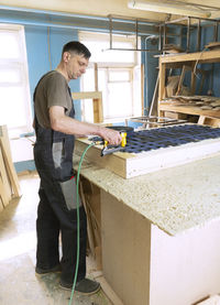 Stapling elastic band with a pneumatic stapler. furniture manufacture shop. vertical orientation.