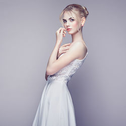 Portrait of young woman standing against gray background