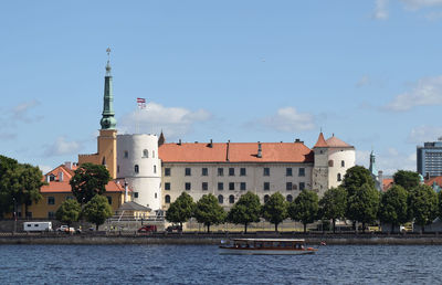 Buildings by river against sky in city