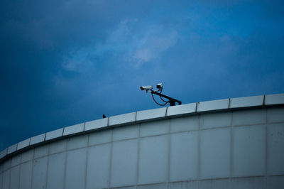 Low angle view of man climbing on building against sky