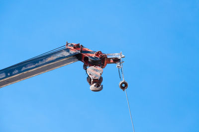 Low angle view of men on rope against clear blue sky