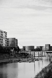 Bridge over river by buildings in city against sky