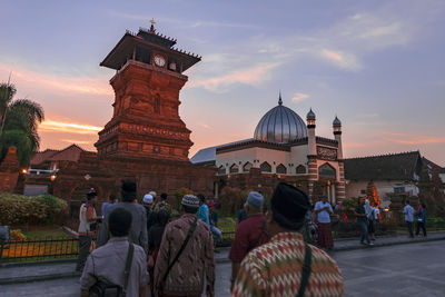 Group of people outside temple against sky during sunset