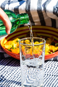 Close-up of hand pouring water in glass on table