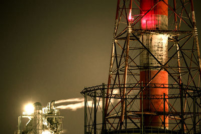 Illuminated smoke stack against sky at night