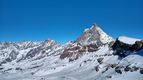 Scenic view of snowcapped mountains against clear blue sky