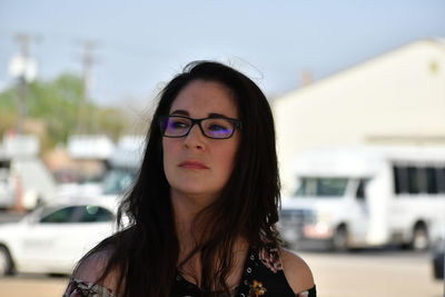 Portrait of young woman standing against buildings