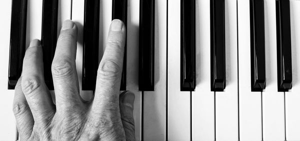 Cropped hand of woman playing piano