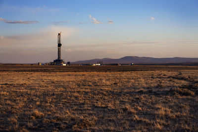 Power plant on field against sky during sunset