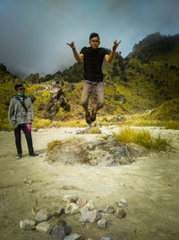 Full length of man jumping on rock against sky