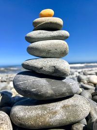 Stack of stones on pebbles at beach against sky