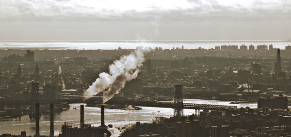 Smoke emitting from chimney in city against sky