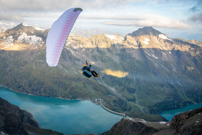 Man paragliding over mountains against sky