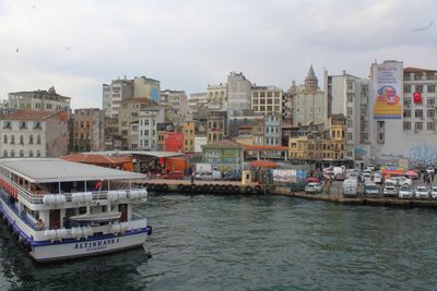 Boats in sea by cityscape against sky