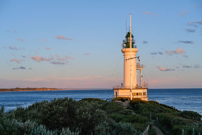 Lighthouse by sea against sky