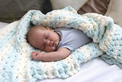 Newborn infant baby boy in blue bodysuit is sleeping in a crib. happy baby.