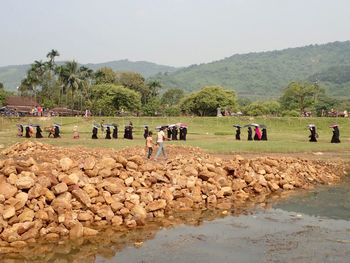 Group of people by river against sky