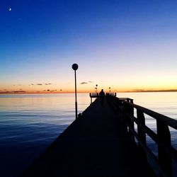 Silhouette pier over sea against sky during sunset