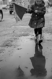 Reflection of boy walking in puddle