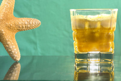 Cropped image of starfish by drink on grass table