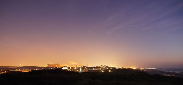 Illuminated factory against sky at night