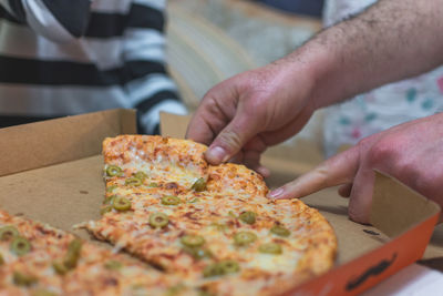 Close-up of hand taking pizza from box