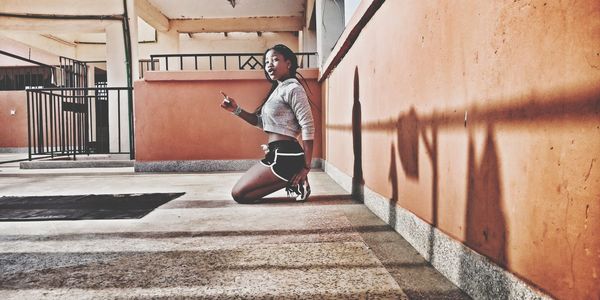 Full length of young man sitting on wall