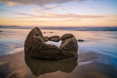 Heart shape on rock by sea against sky during sunset