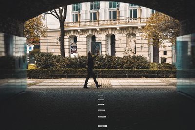 Rear view of man walking on road amidst buildings