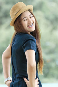 Cheerful young woman with braces wearing hat outdoors