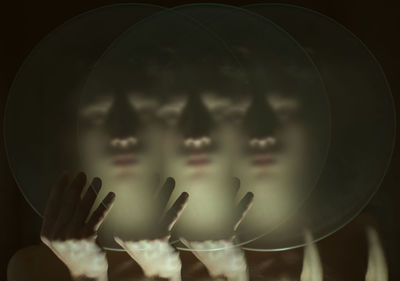 Multiple image of woman holding glass against black background