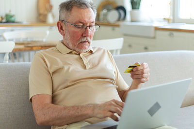Man using laptop while sitting on sofa at home
