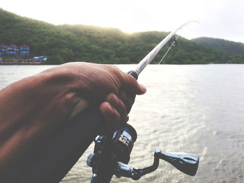 Man holding fishing rod by river